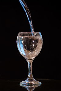 Close-up of wineglass in glass against black background