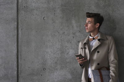 Young model holding mobile against wall