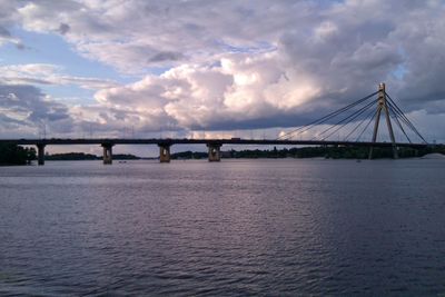 View of bridge over calm sea against cloudy sky