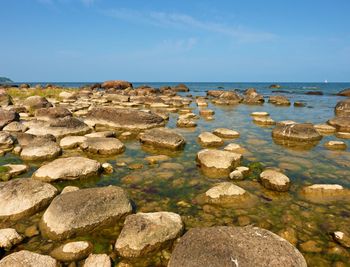 Big boulders in shore in smooth wavy sea. stony coastline, clear sky.