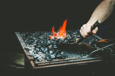 Cropped hand of man preparing barbecue at night