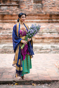 Full length of holding bouquet while standing outdoors