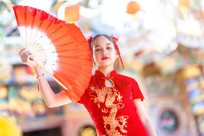 Midsection of woman holding red while standing against blurred background