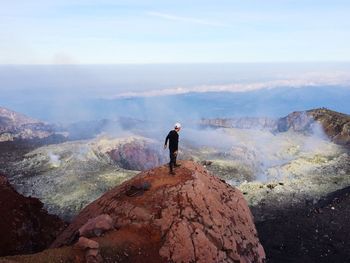 Man standing on rock against sky