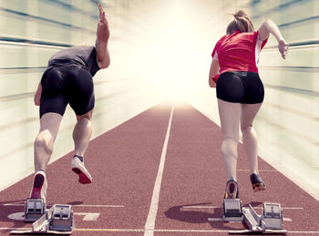 Rear view of people running on track