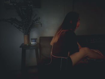 Side view of young woman using phone at home