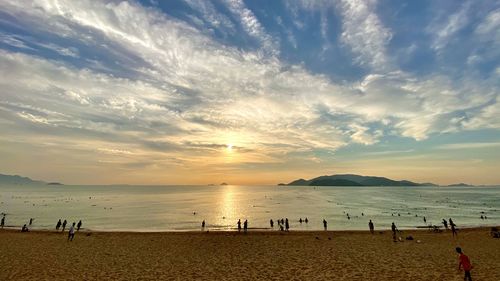People on beach against sky during sunset