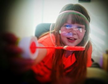 Portrait of smiling girl playing with bubble on wand at home