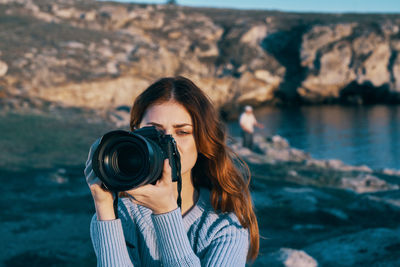 Portrait of young woman holding rock at sea shore