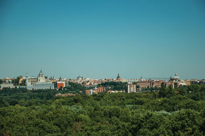 Building skyline on the horizon with green treetops seen from the teleferico park of madrid, spain.