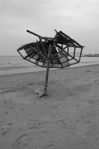 Traditional windmill on beach against sky