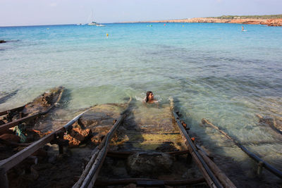 Girl by sea in summer in a swimsuit among the crystal clear waters of formentera in cala saona water