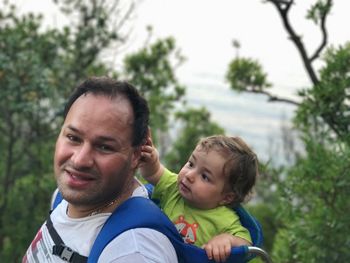 Side view of father carrying son while hiking on mountain