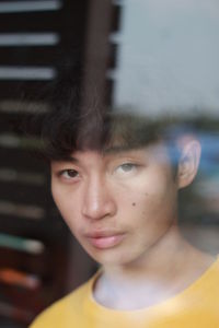 Close-up portrait of young man looking through window