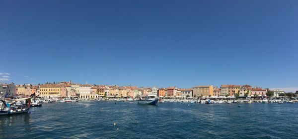 Sea by cityscape against clear blue sky