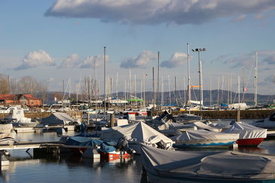 Boats moored at harbor against sky