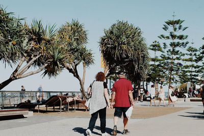 People walking on footpath against clear sky