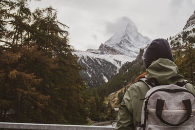 Rear view of person looking at snowcapped mountain