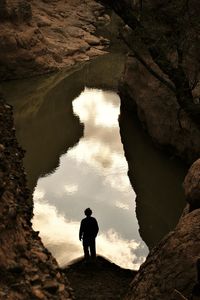 Rear view of man standing on cliff against sky