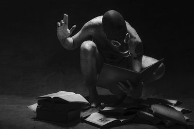 Man reading book while wearing gas mask in darkroom