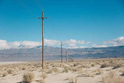 Electricity pylon on landscape against blue sky