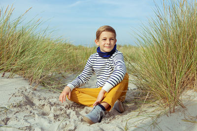 Full length of boy sitting on sand