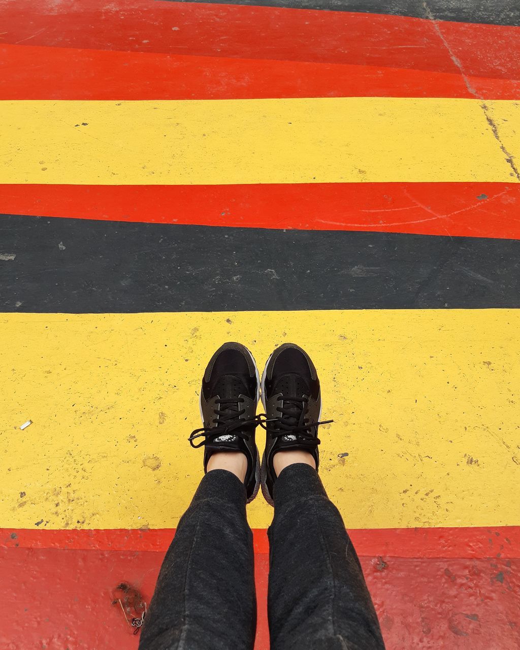 LOW SECTION OF MAN STANDING ON YELLOW ROAD