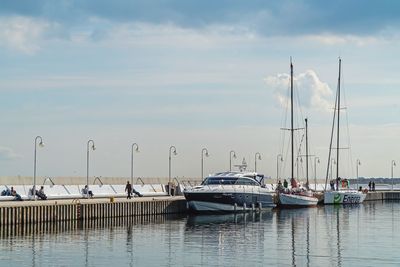 Boats moored at harbor against sky