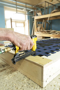 Stapling elastic band with a yellow pneumatic stapler. furniture manufacture. vertical orientation.