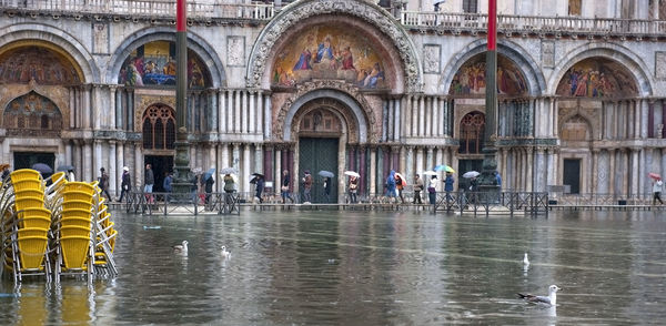 Chairs on water filled walkway against st marks cathedral during flood