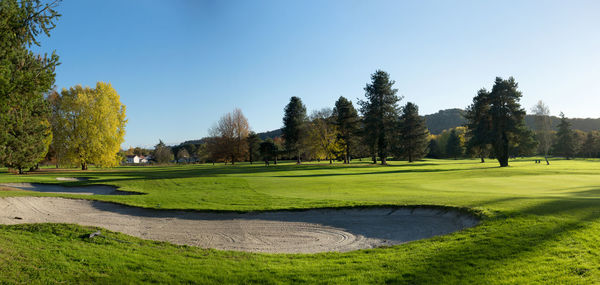 Scenic view of golf course against clear sky