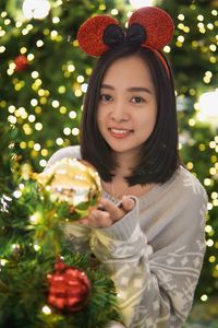 Portrait of young woman holding christmas tree