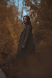 Young woman standing against trees