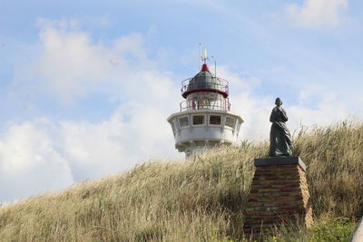 Lighthouse on field against sky