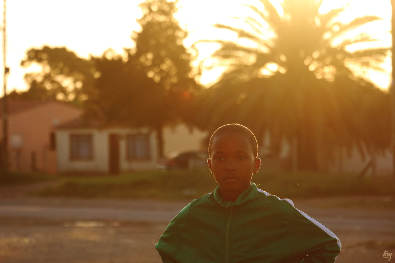 PORTRAIT OF BOY ON TREE DURING SUNSET