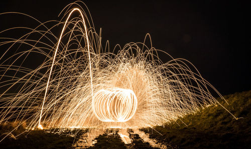 Wire wool spinning against sky at night