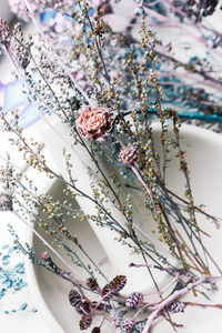 Delicate toned dried flowers in a large white ceramic mortar with pestle. vintage pastel background.