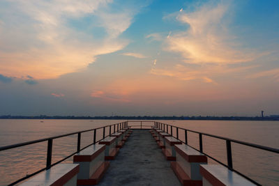 Pier over sea against sky during sunset