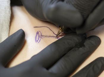 Cropped hand of woman holding insect on bed