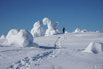 Person on snowcapped mountain against clear blue sky