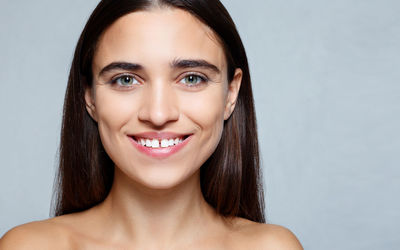 Close-up portrait of a smiling young woman over white background