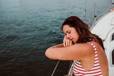 Side view of woman sleeping in boat on sea