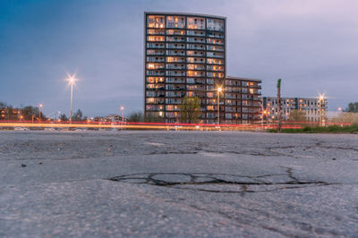 Illuminated city by buildings against sky at dusk