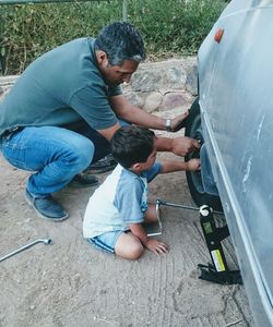 Father and son changing tire together