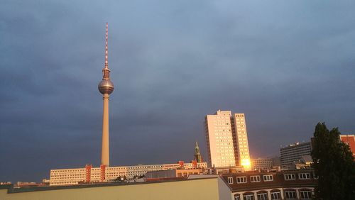 Communications tower in city against sky