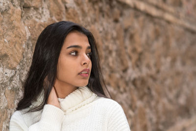 Portrait of beautiful young woman against wall