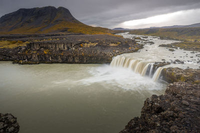 Scenic view of waterfall against sky