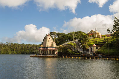 Building by river against cloudy sky