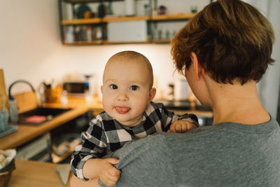 A mother holds her daughter in her arms in the kitchen.