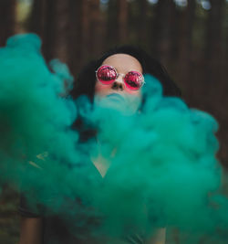 Portrait of young woman wearing sunglasses standing in forest